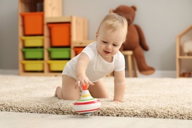 Children toys. Cute little boy playing with spinning top on rug at home