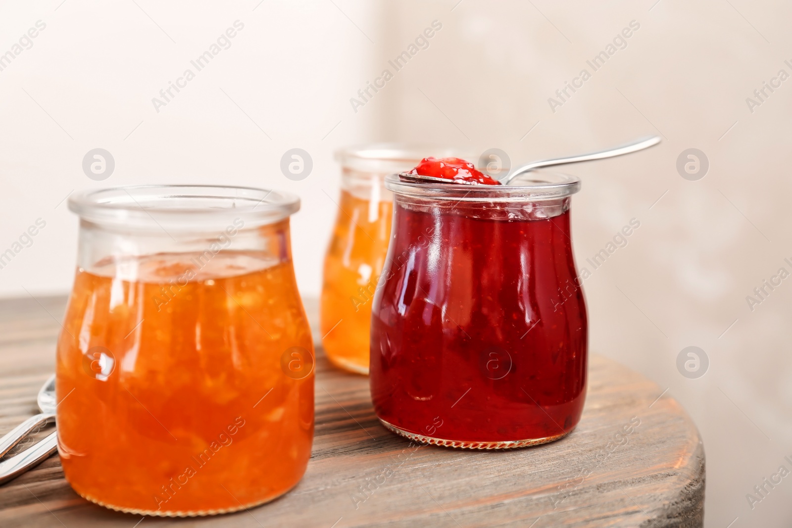 Photo of Jars with tasty sweet jam on wooden table