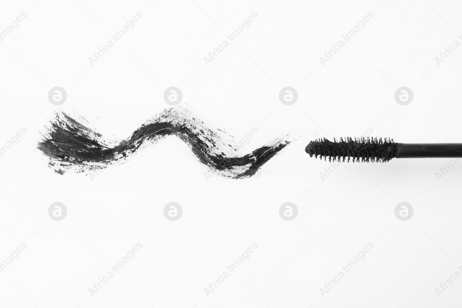 Photo of Applicator and black mascara smear for eyelashes on white background, top view