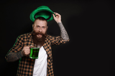 Photo of Bearded man with green beer on black background, space for text. St. Patrick's Day celebration