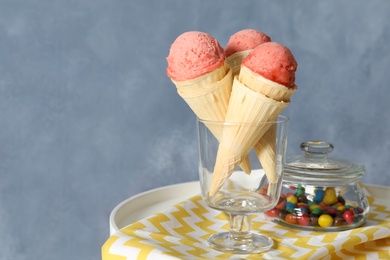 Photo of Delicious pink ice cream in wafer cones and candies on white table. Space for text