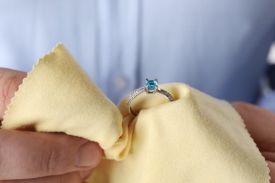 Jeweler cleaning topaz ring with microfiber cloth, closeup