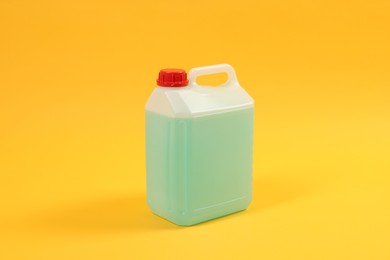 Plastic canister with green liquid on orange background
