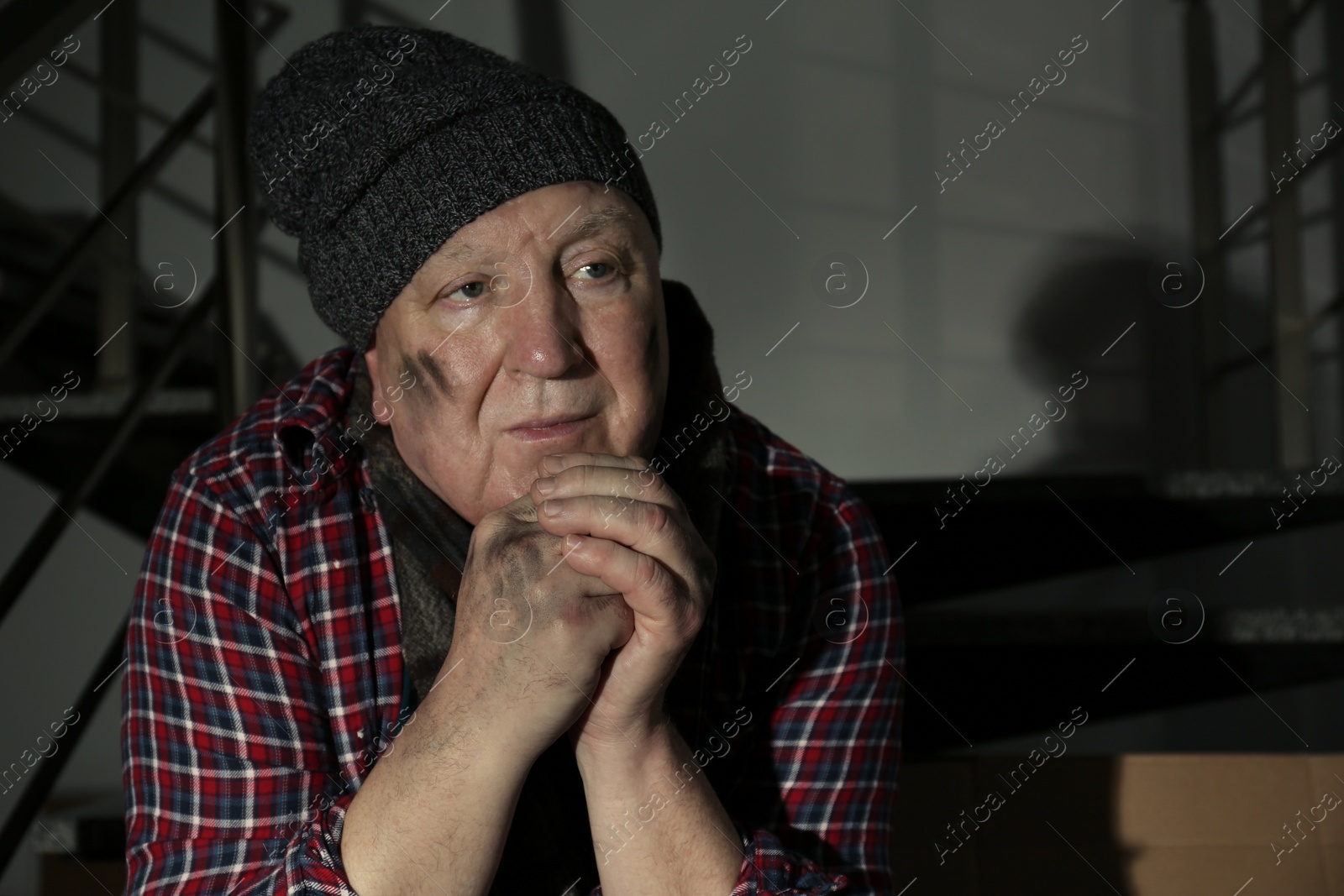 Photo of Portrait of poor man sitting on stairs indoors. Space for text