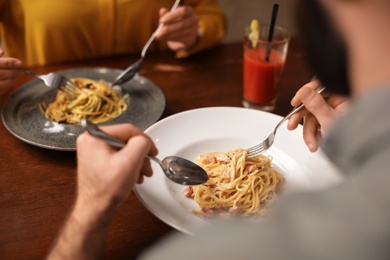 Photo of Lovely young couple having pasta carbonara for dinner at restaurant, closeup view