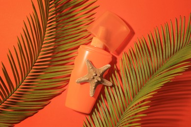 Sunscreen, starfish and tropical leaves on coral background, flat lay. Sun protection care