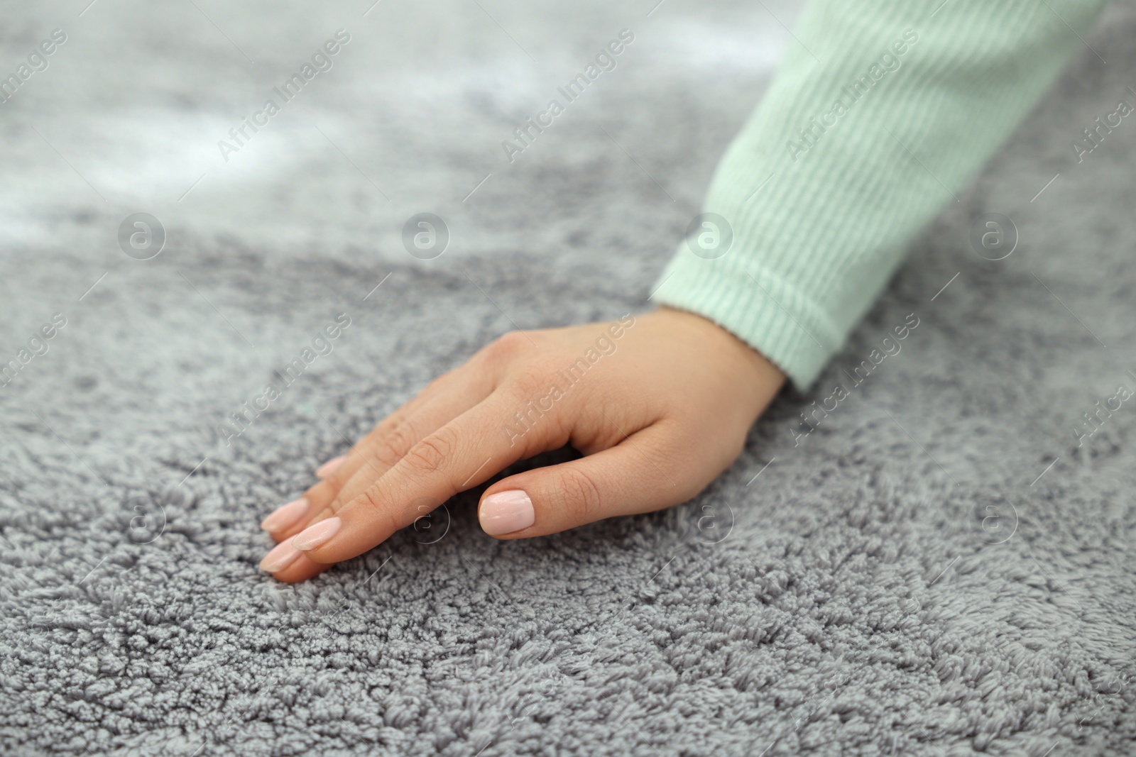 Photo of Woman touching soft grey carpet, closeup view