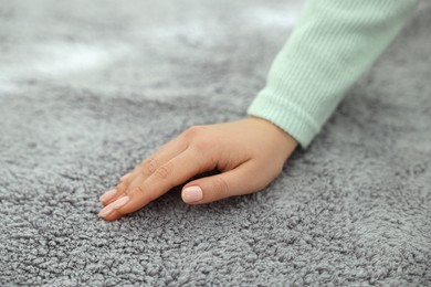 Woman touching soft grey carpet, closeup view