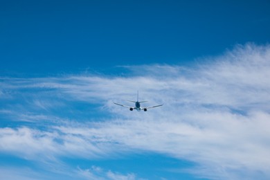 Photo of Modern white airplane flying in cloudy sky