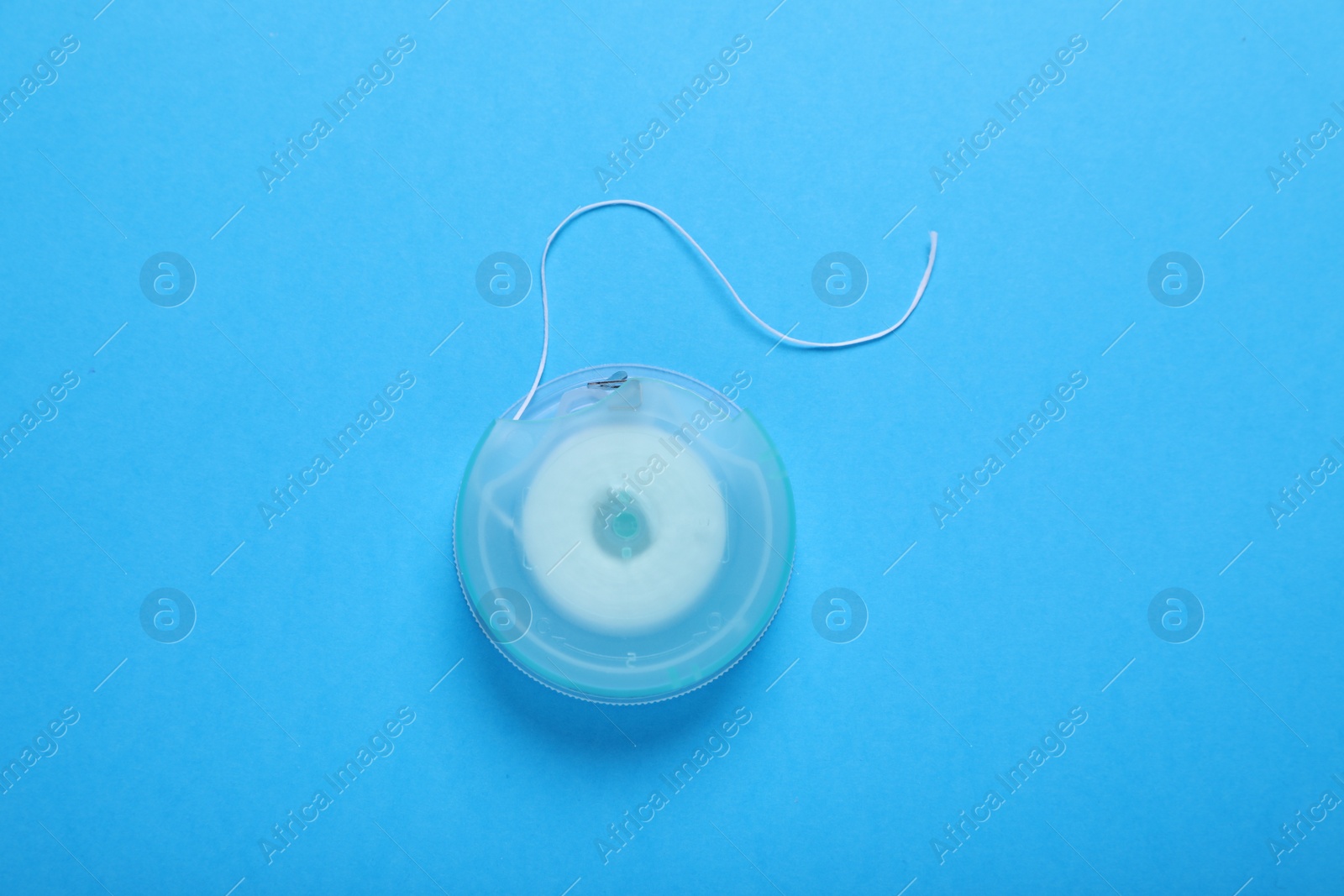 Photo of Container with dental floss on light blue background, top view