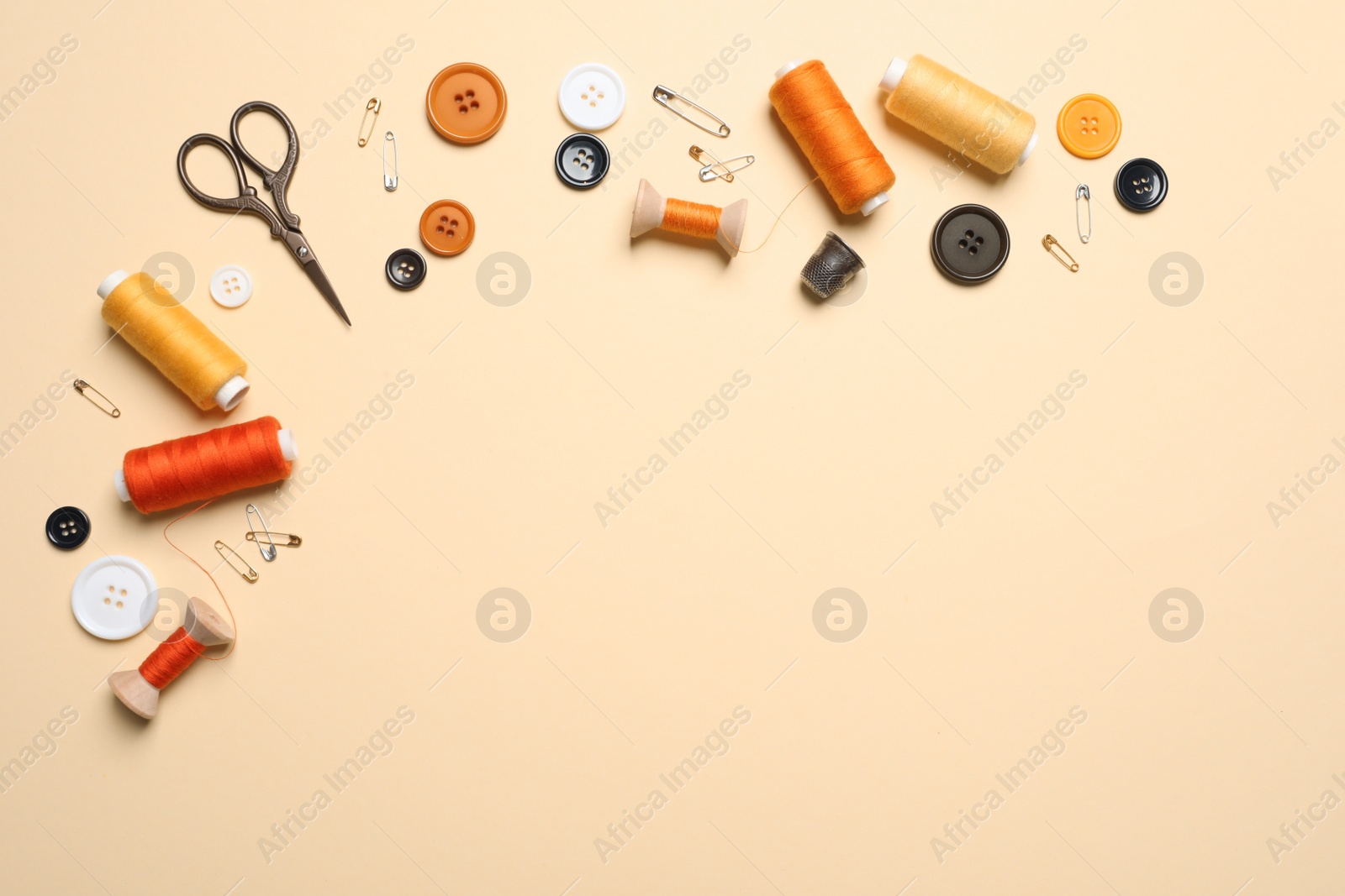 Photo of Flat lay composition with scissors and other sewing accessories on light yellow background, space for text