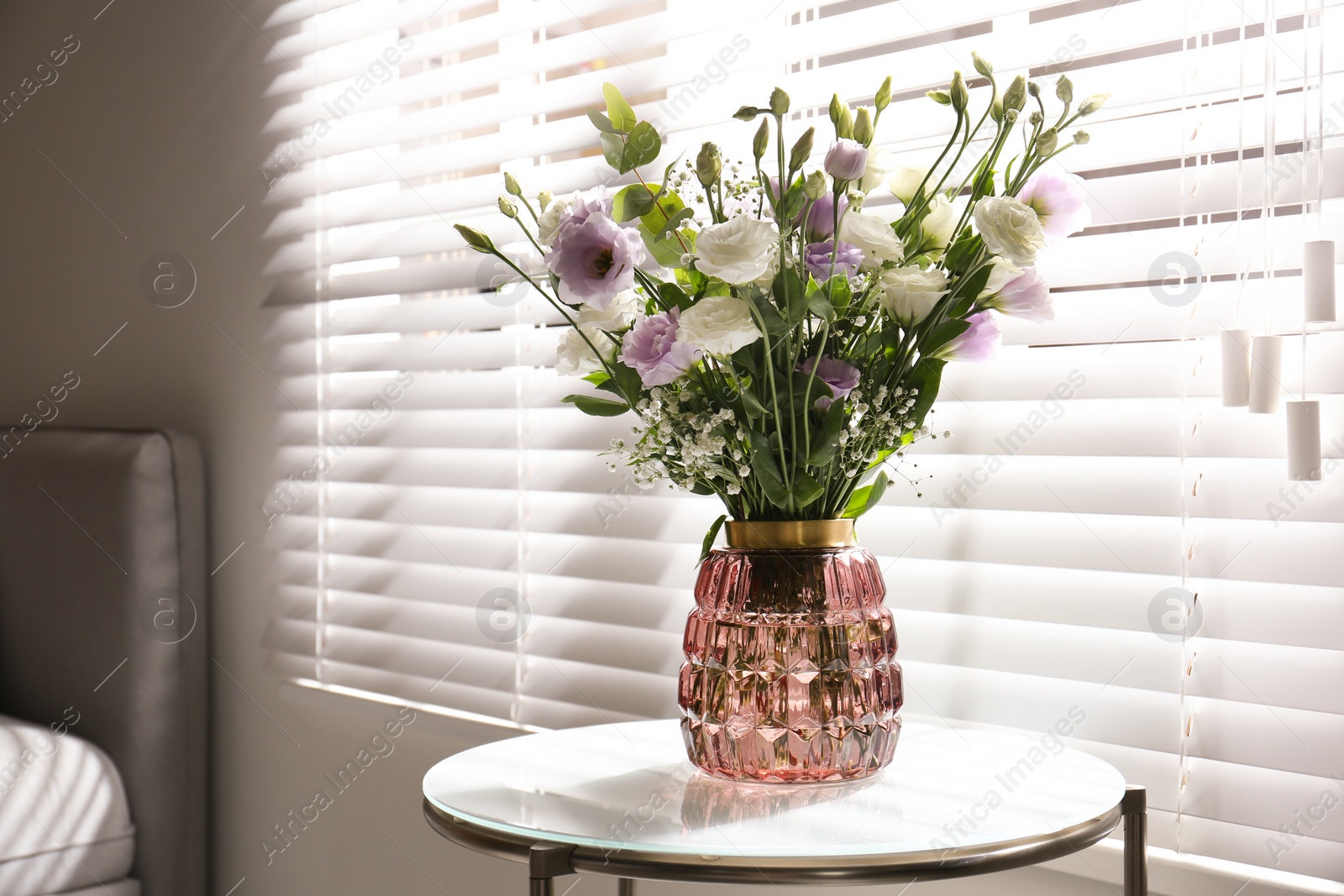 Photo of Bouquet of beautiful Eustoma flowers on table in room. Space for text