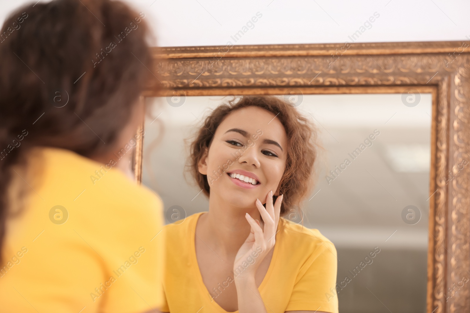 Photo of Beautiful young woman with acne problem looking in mirror at home