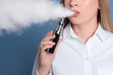 Photo of Young woman using electronic cigarette on light blue background, closeup