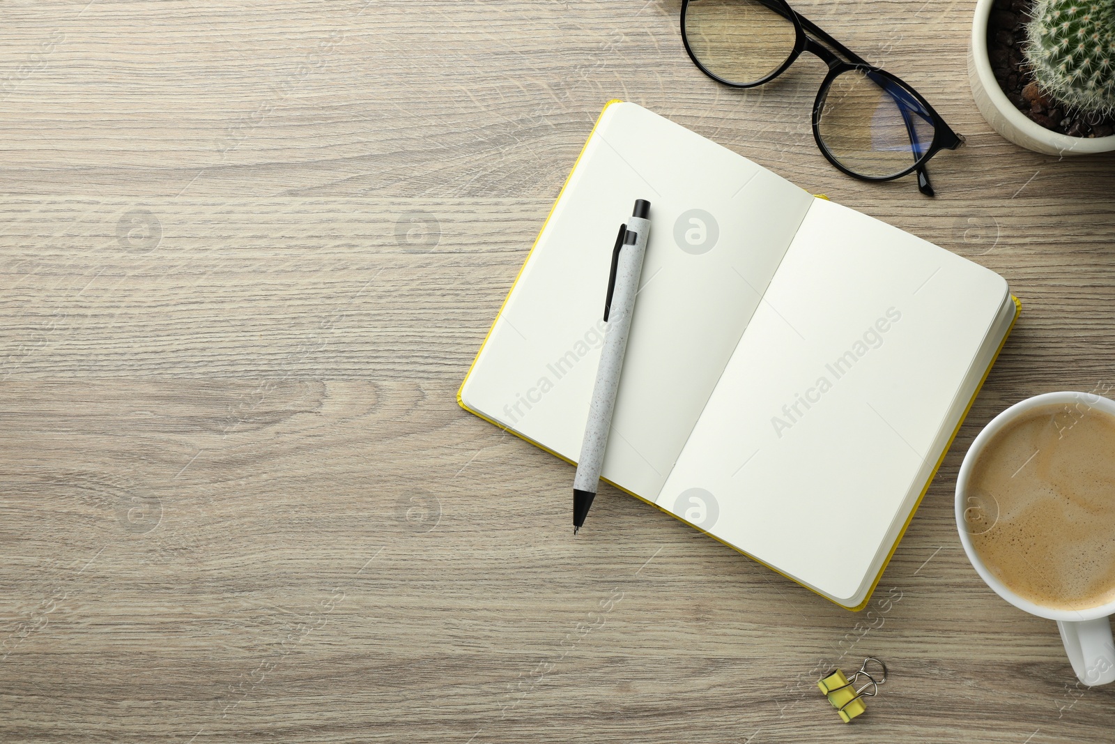 Photo of Open notebook, pen, glasses and cup of coffee on wooden table, flat lay. Space for text