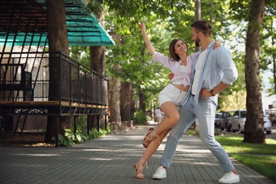 Photo of Lovely young couple dancing together outdoors on sunny day