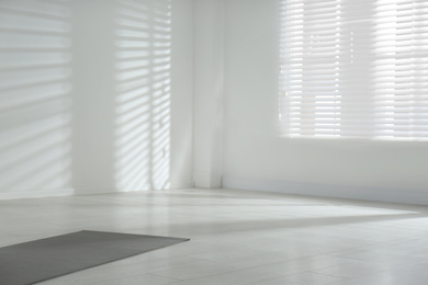 Unrolled grey yoga mat on floor in room. Space for text