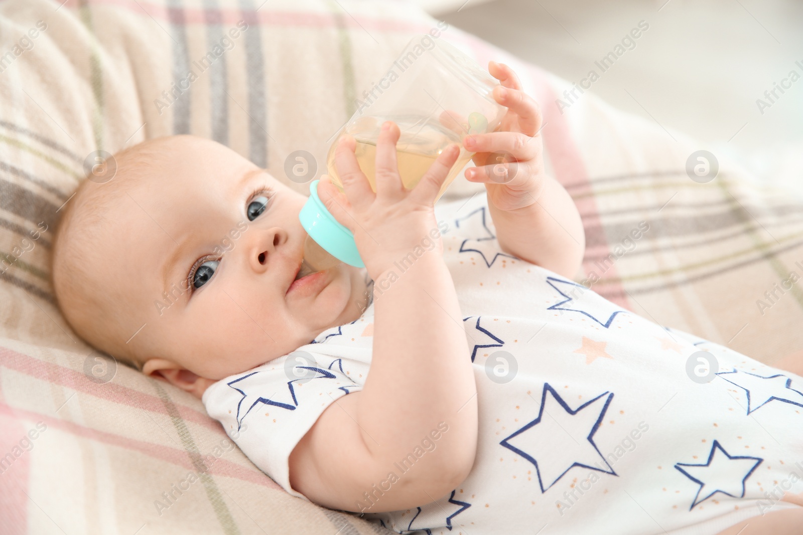 Photo of Pretty baby drinking from bottle on bed at home