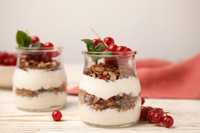 Photo of Delicious yogurt parfait with fresh red currants and mint on white wooden table