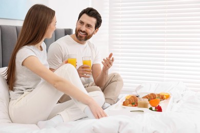 Photo of Happy couple having breakfast and talking in bedroom. Space for text