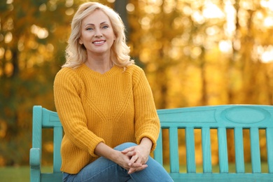 Portrait of happy mature woman on bench in park