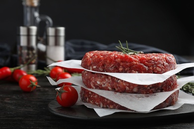 Photo of Raw meat cutlets for burger on black wooden table