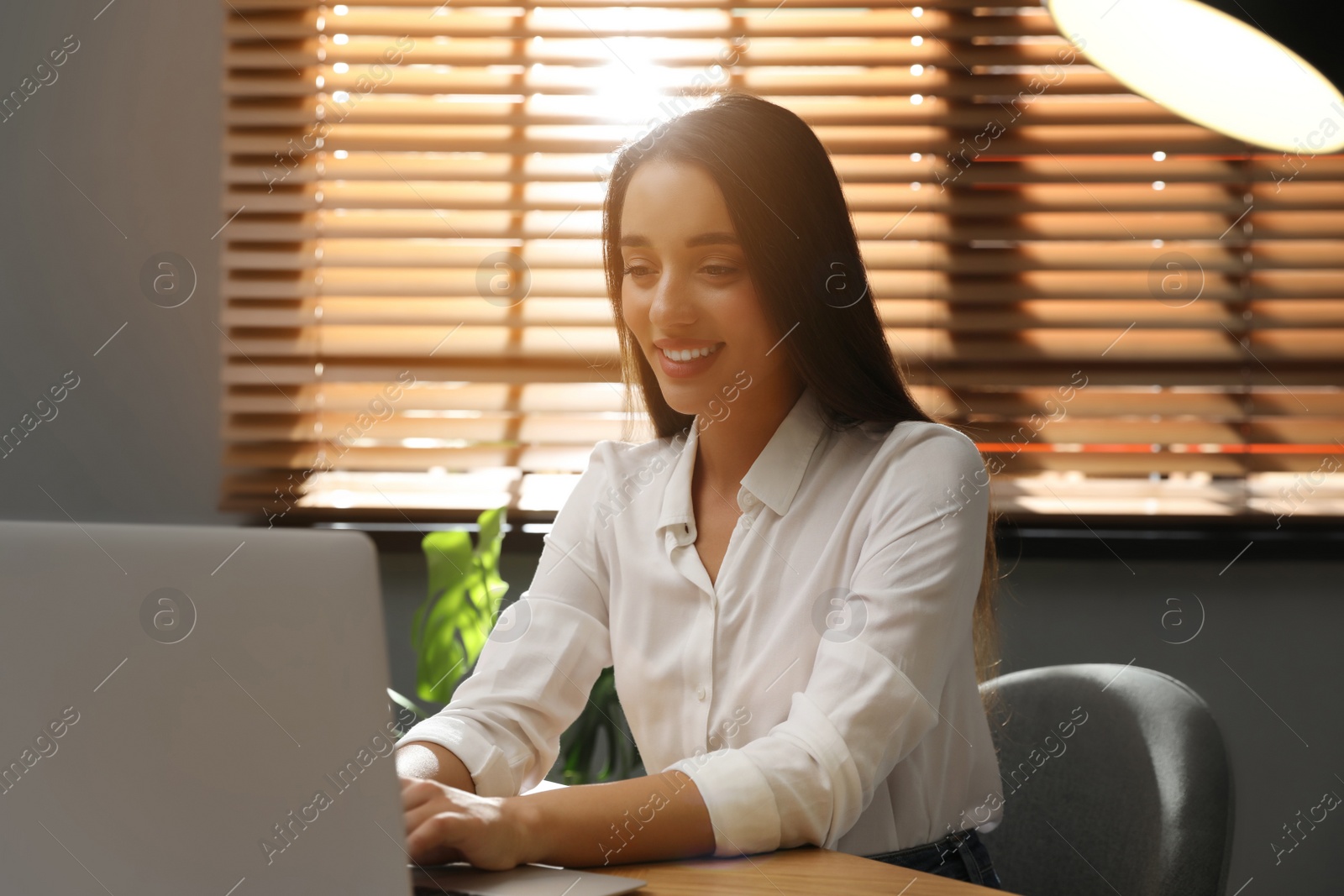 Photo of Young woman using laptop for search at wooden table in office