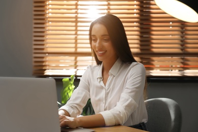 Young woman using laptop for search at wooden table in office