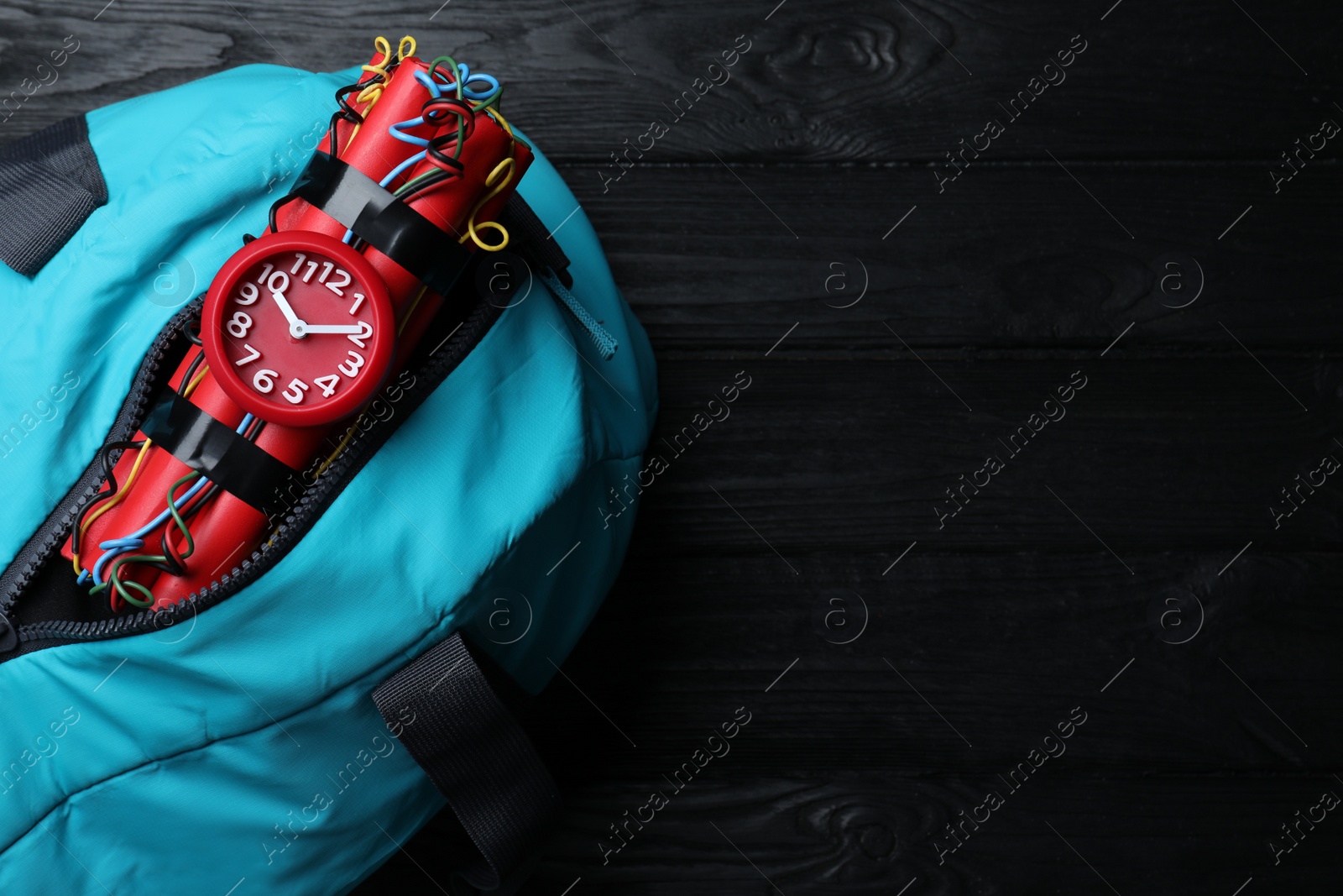 Photo of Blue sportive bag with dynamite time bomb on black wooden table, top view. Space for text