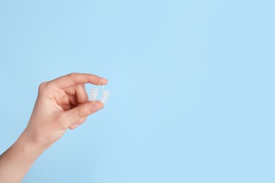 Photo of Woman holding anti-snoring device on light blue background, closeup. Space for text