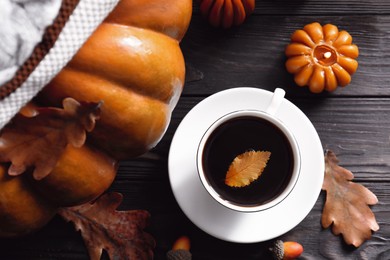 Cup of hot drink and pumpkin shaped candles on wooden table, flat lay. Cozy autumn atmosphere