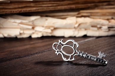 Old vintage key and book on wooden background, space for text