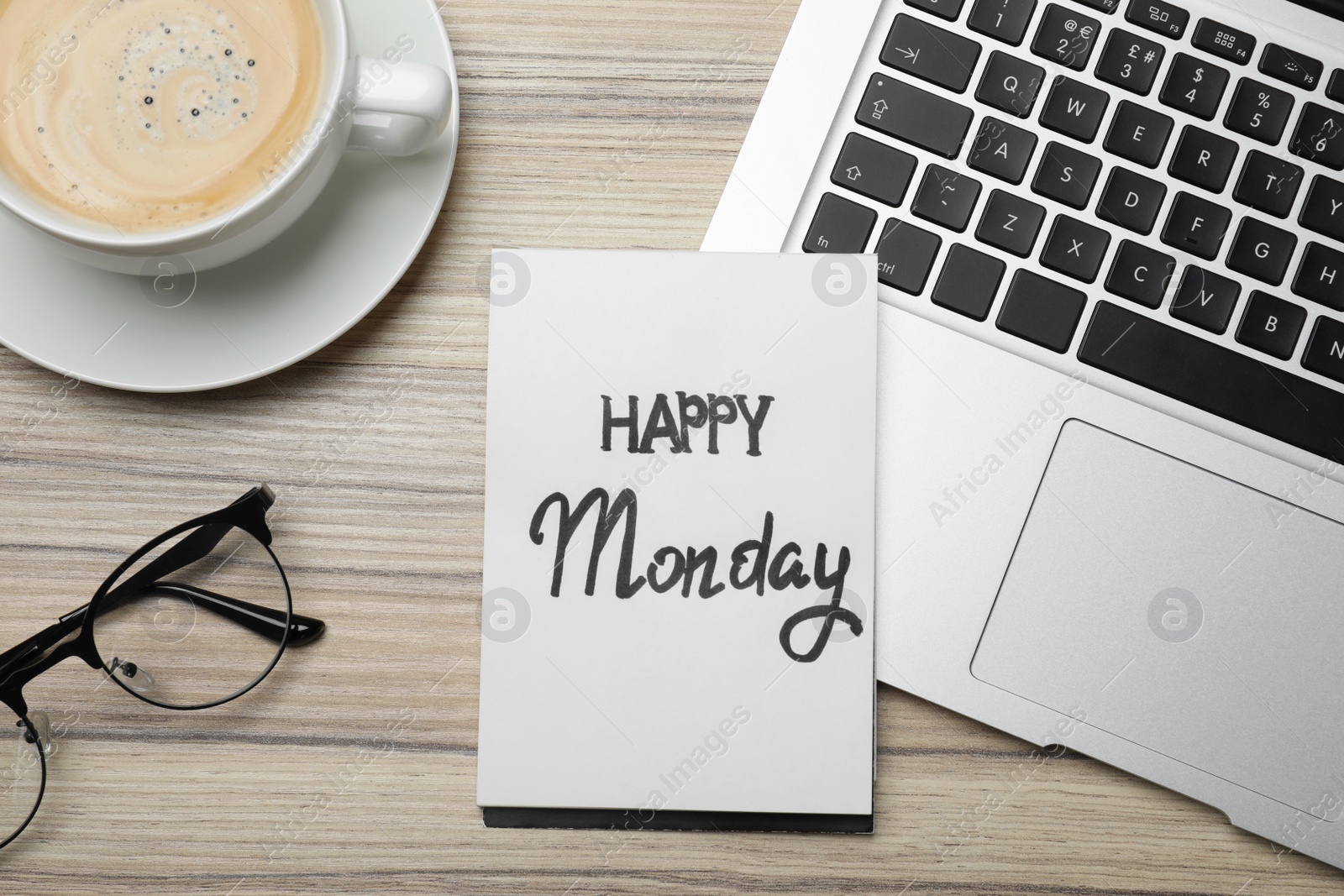 Photo of Message Happy Monday written in notebook, laptop and cup of coffee on wooden desk, flat lay