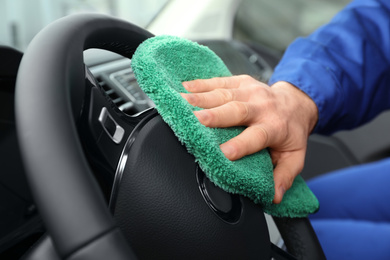 Car wash worker cleaning automobile interior, closeup