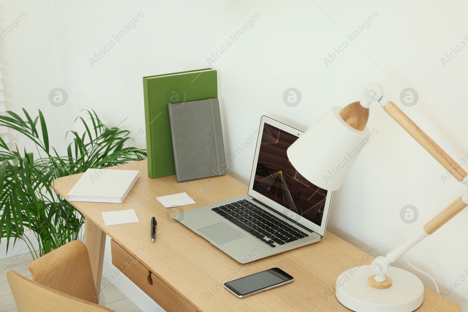 Photo of Cozy workspace with laptop, smartphone and lamp on wooden desk at home