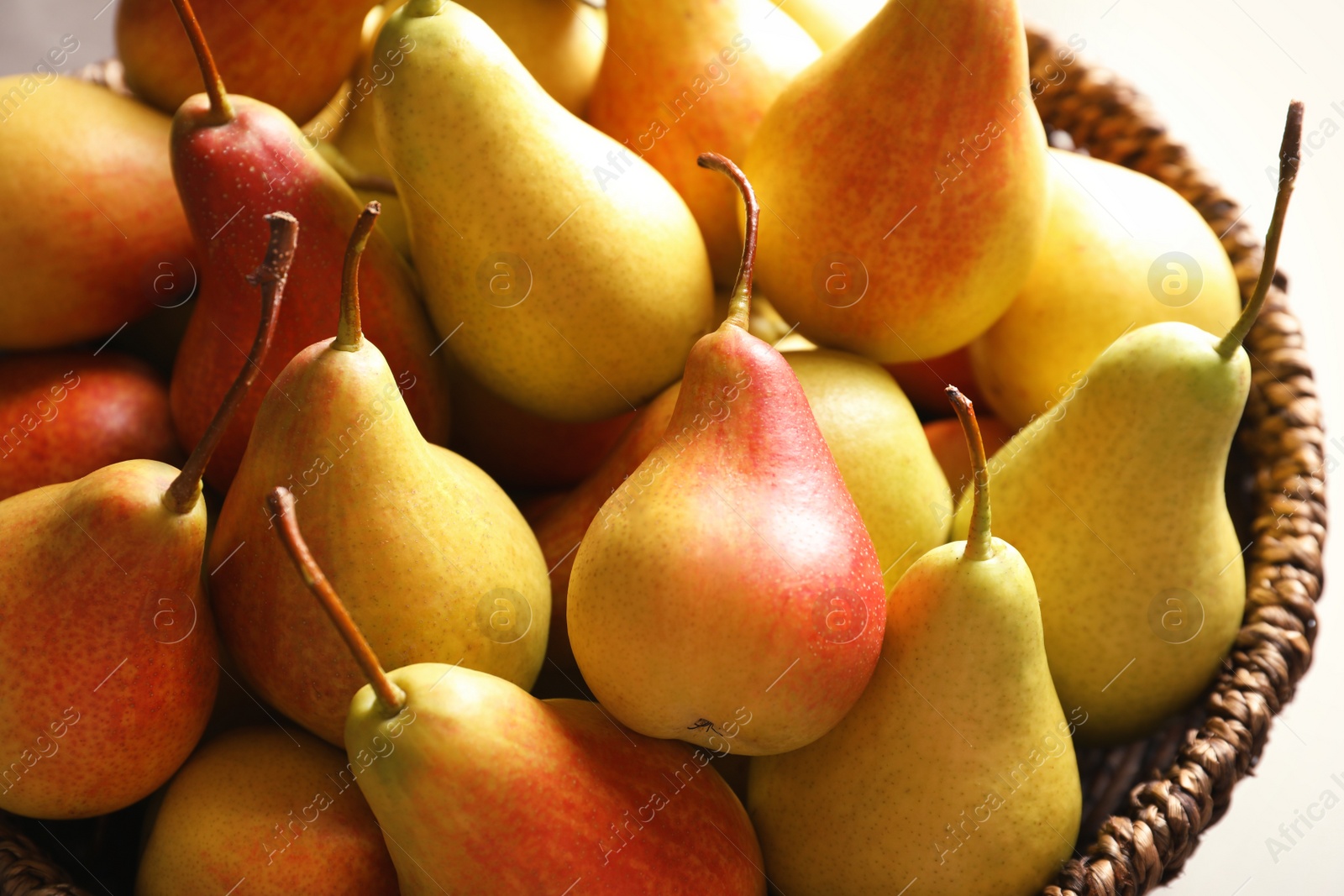 Photo of Wicker bowl with ripe pears, closeup. Healthy snack