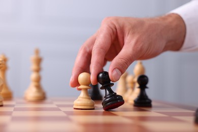 Photo of Man with game pieces playing chess at checkerboard, closeup