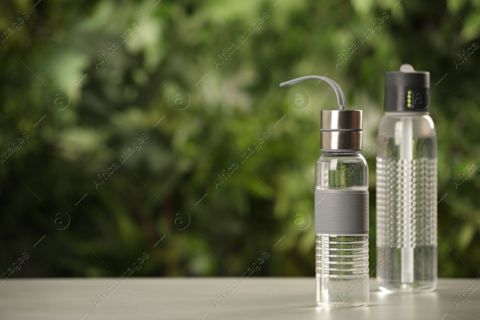 Photo of Sport bottles of water on white wooden table outdoors, space for text