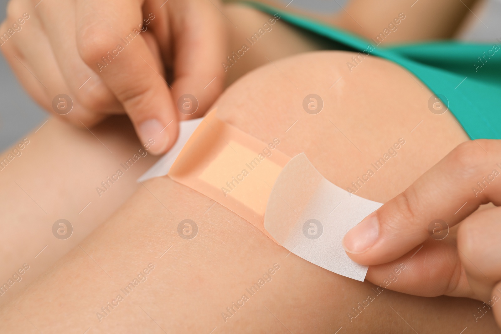 Photo of Woman applying plaster on knee, closeup view