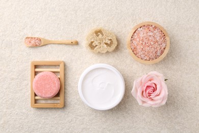 Photo of Flat lay composition with moisturizing cream in open jar and other body care products on light textured table