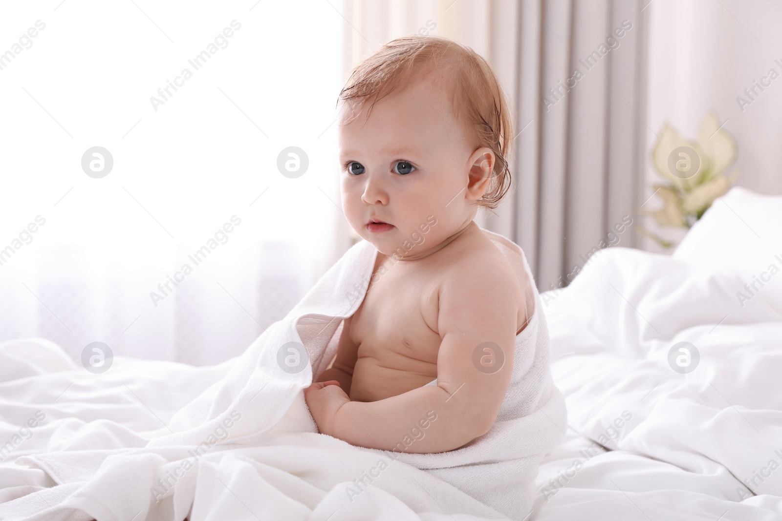Photo of Cute little baby with soft towel on bed after bath