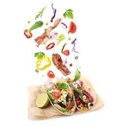 Image of Delicious tacos. Ingredients falling into tortillas on white background