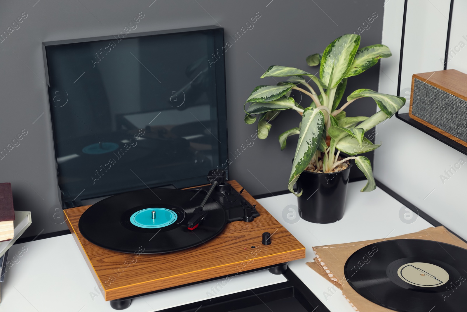 Photo of Stylish turntable with vinyl disc near grey wall in room