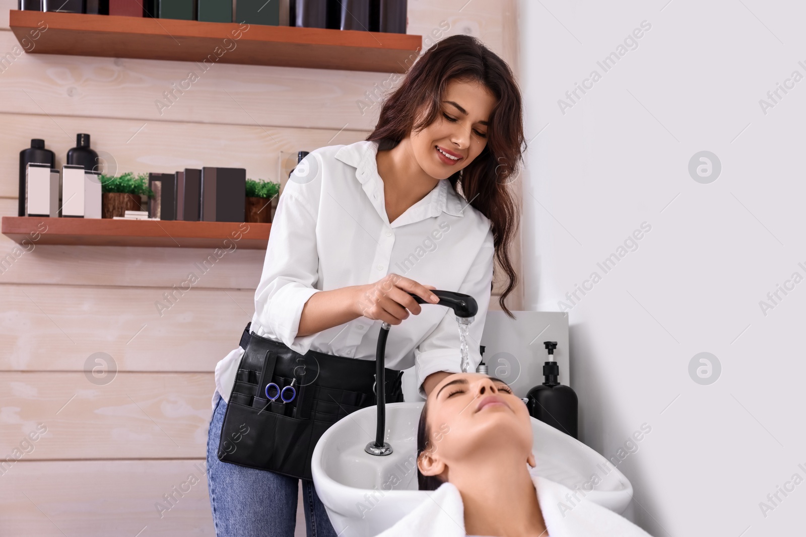 Photo of Professional hairdresser washing woman's hair in beauty salon