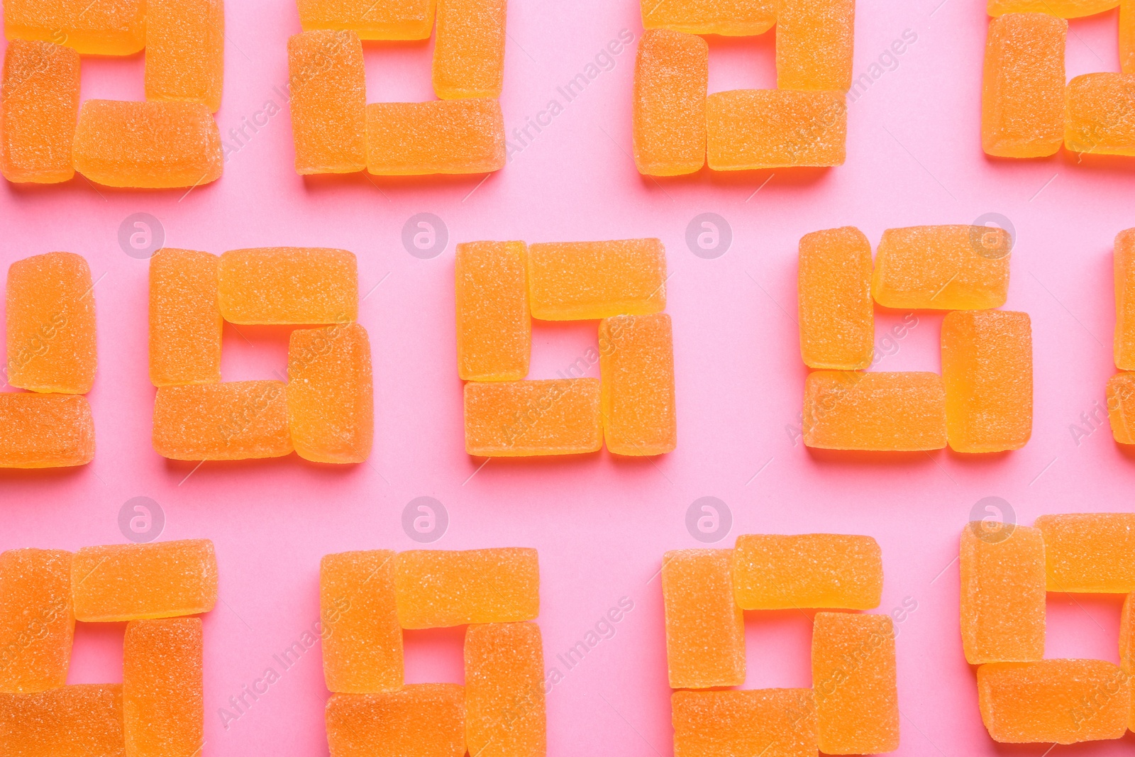 Photo of Tasty orange jelly candies on pink background, flat lay