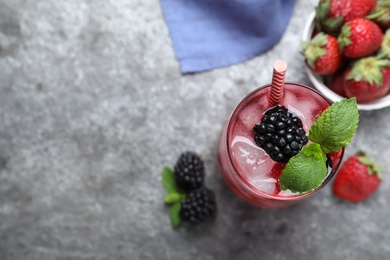 Photo of Flat lay composition of delicious strawberry lemonade with soda water, mint and blackberries on grey table, space for text. Fresh summer cocktail