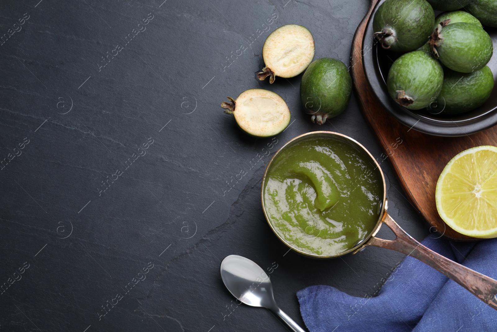 Photo of Feijoa jam and fresh fruits on black table, flat lay. Space for text