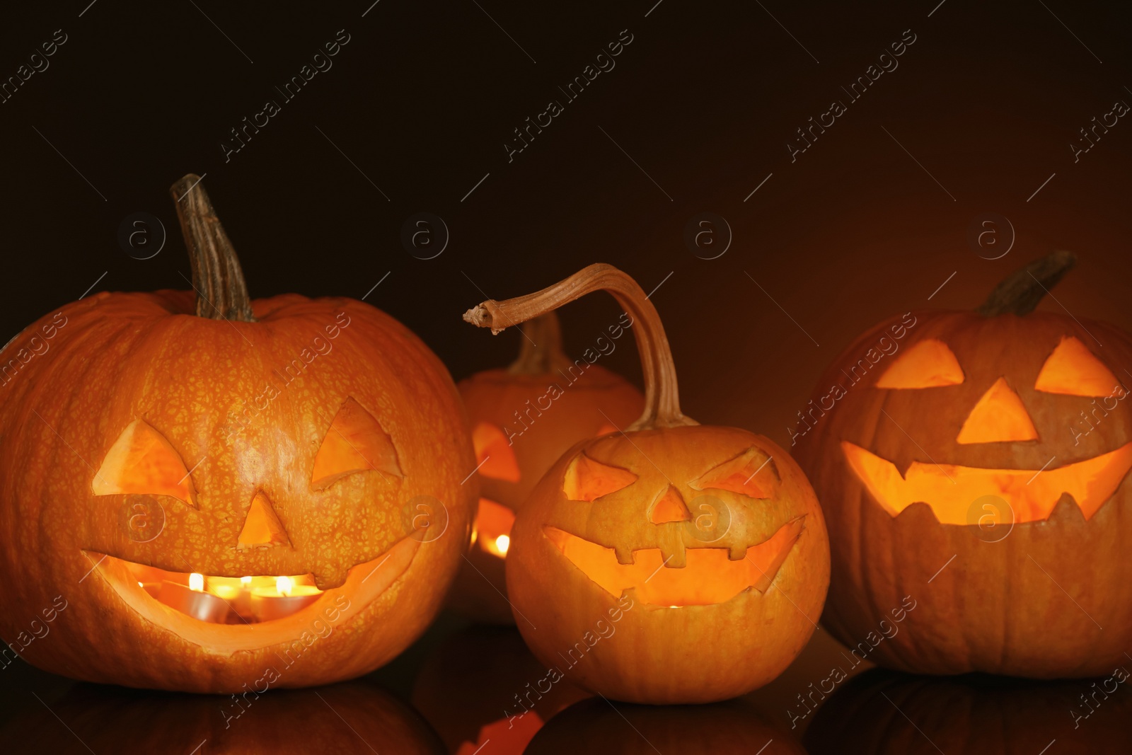 Photo of Halloween pumpkin heads. Glowing jack lanterns on dark background