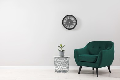 Photo of Comfortable armchair and coffee table near light grey wall indoors. Space for text