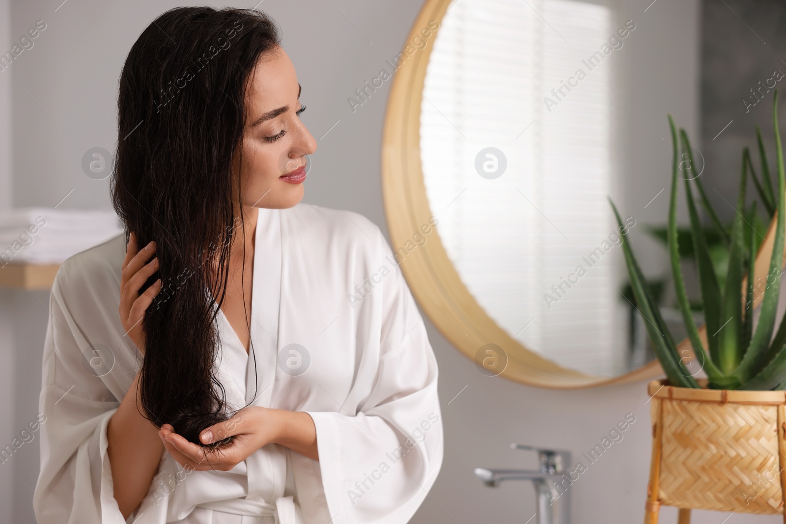 Photo of Young woman applying cosmetic hair mask in bathroom. Space for text